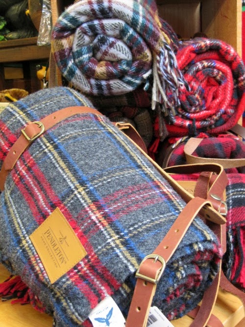 Three tartan plaid blankets rolled with a leather carrying strap.