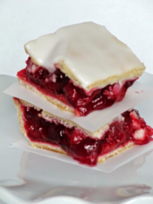 Two slices of cherry slab pie on a white plate.
