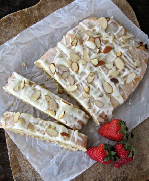 Almond Braid pastry on a cutting board with red strawberries. 