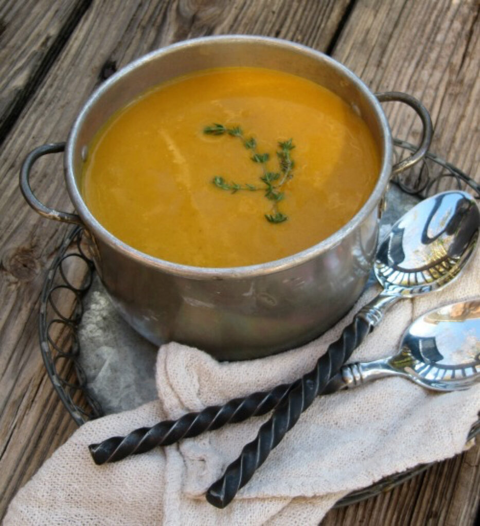 Roasted butternut squash soup with herbs and spices in a small silver pot