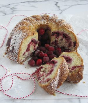 cranberry swirl bundt cake with 2 slices on a marble counter.