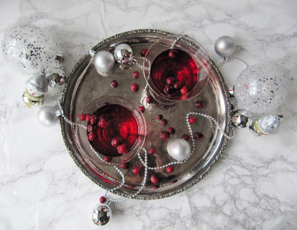 Cranberry cordial in 2 glasses on a silver tray.
