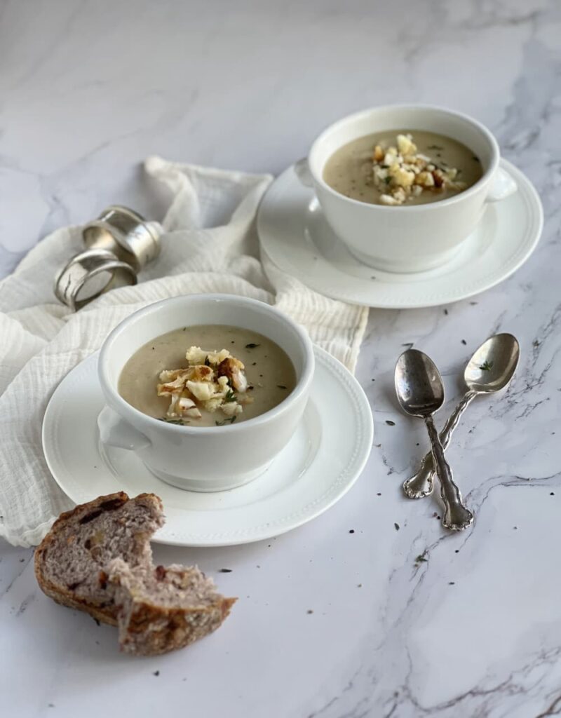 caramelized onion and cauliflower soup in two white bowls.