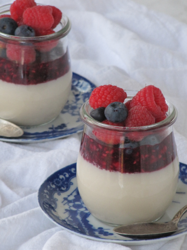 panna cotta with berries in glass jars on blue and white plates