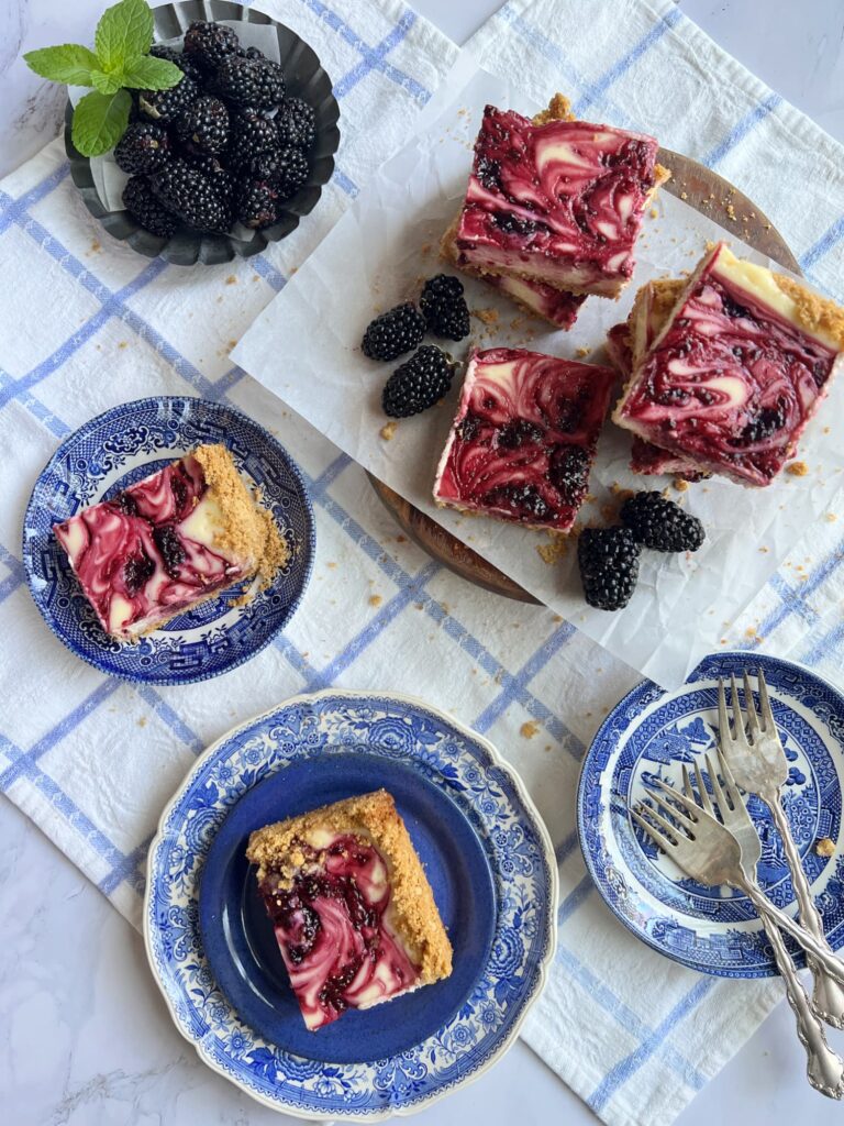 Stack of blackberry cheesecake bars and transferware plates