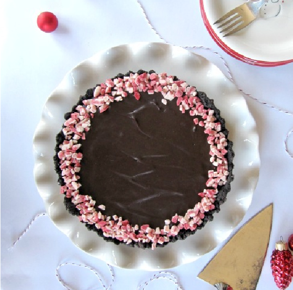 Chocolate-Peppermint-Tart on a white ruffles plate on a white table with red bulbs on the table
