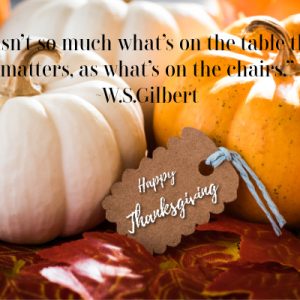 “It isn’t so much what’s on the table that matters, as what’s on the chairs.” quote over an orange and white pumpkin with a tag that says happy thanksgiving