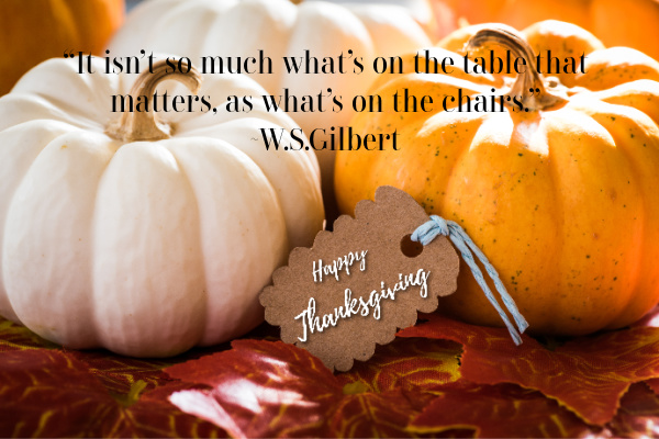 “It isn’t so much what’s on the table that matters, as what’s on the chairs.” quote over an orange and white pumpkin with a tag that says happy thanksgiving