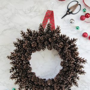 pinecone wreath on wire frame no glue with tartan ribbon scissors and green and red christmas ornaments