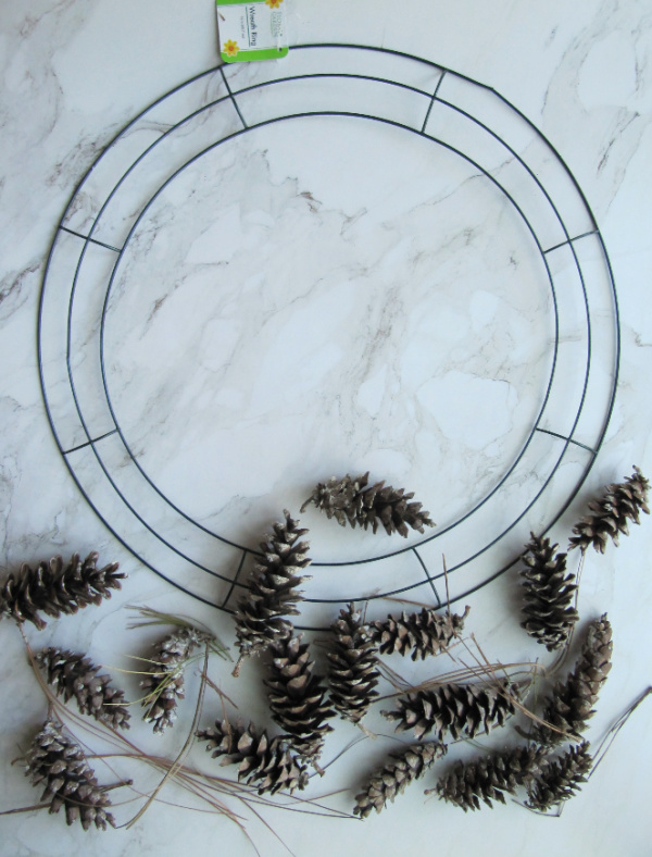 pinecones and a metal wreath form on a marble backround