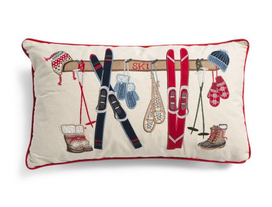 Tan pillow with red piping and ski gear on the front