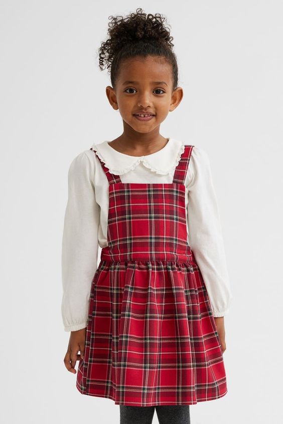 little African American girl wearing a red tartan jumper with a white blouse
