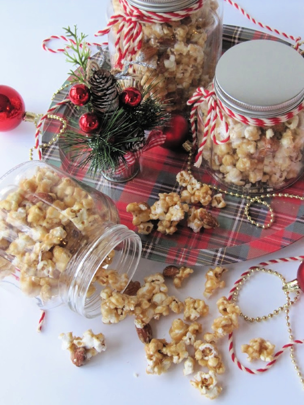 caramel corn spilled on a white surface and in three glass containers on a plaid tray