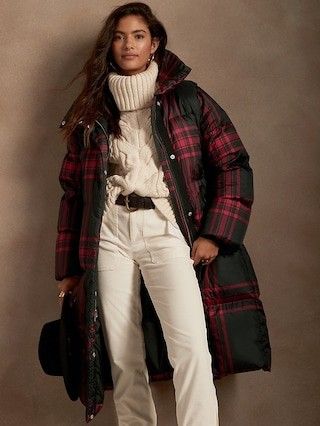 model wearing off white pants cable knit sweater and a burgundy plaid coat