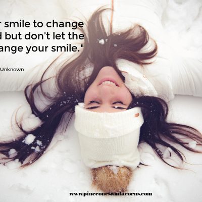 a girl laying in the snow smiling with the quote don't let the world change your smile