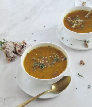 easy roasted butternut squash pumpkin soup in white bowls sitting on a brown cutting board with a white cloth in the right hand corner and a small bowl of pecans