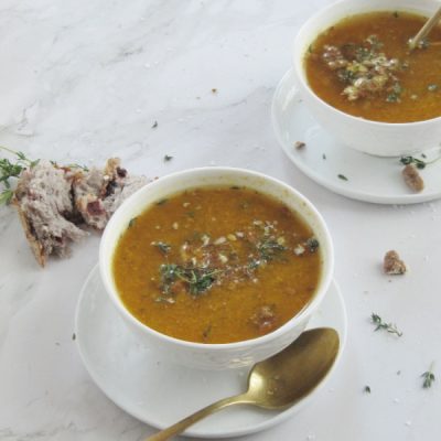 easy roasted butternut squash pumpkin soup in white bowls sitting on a brown cutting board with a white cloth in the right hand corner and a small bowl of pecans