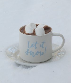 hot chocolate and marshmallows in a let it snow mug on a snow topped table