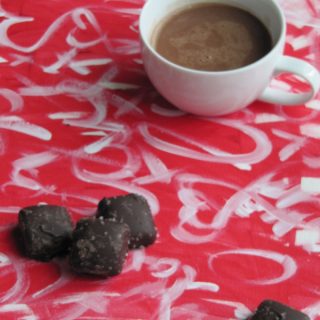 cup of chocolate and chocolate caramels on a red and white painting