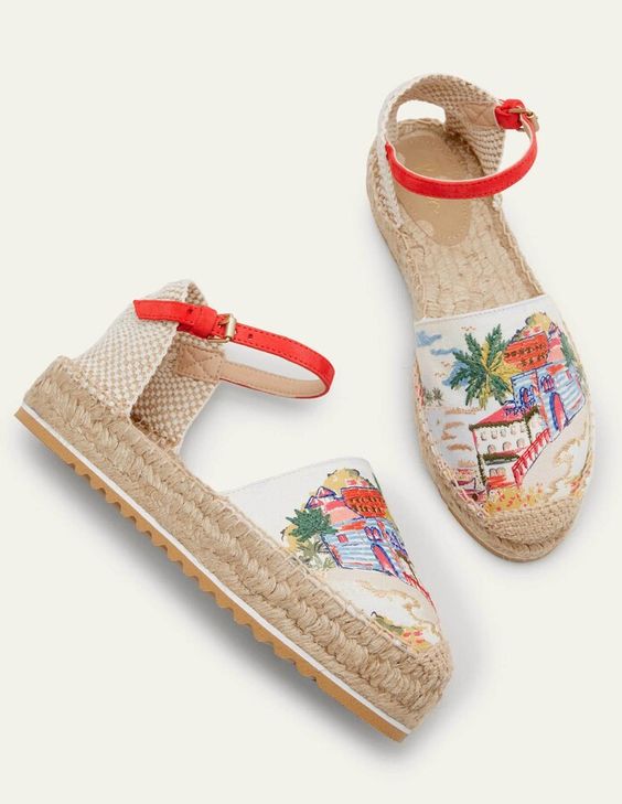 pair of white espadrilles with a colorful village scene