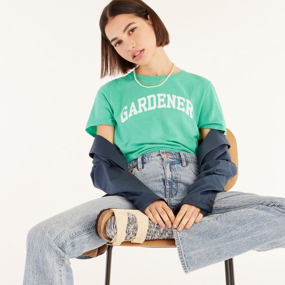 Girl sitting on a chair wearing jeans and a green shirt with white letters gardner