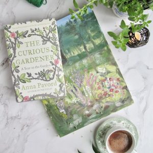 A Flatlay with The Curious Gardner book, acrylic painting, herbs and hot chocolate