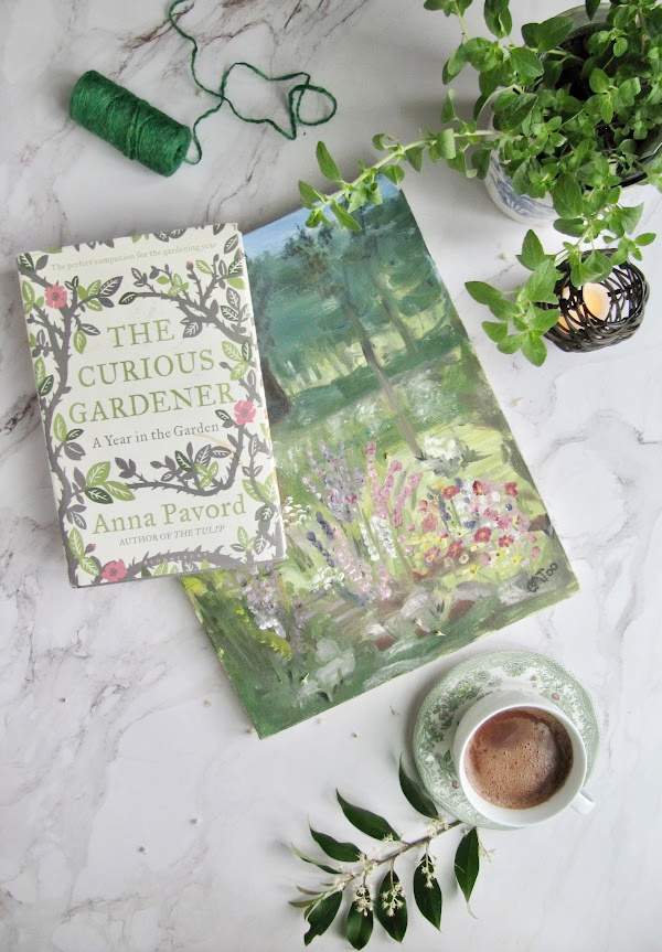 A Flatlay with The Curious Gardner book, acrylic painting, herbs and hot chocolate