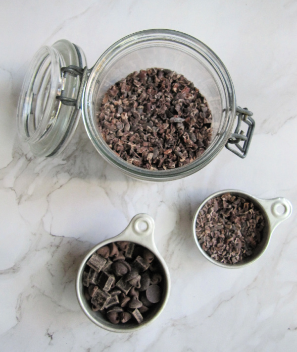 jar of cocoa nibs and cup of chocolate chips