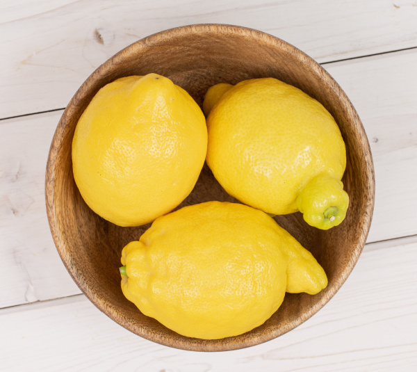 three lemons in a wood bowl