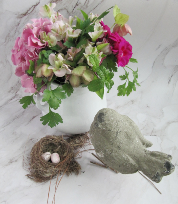 white ironstone pitcher with spring flowers concrete bird and a nest with two eggs