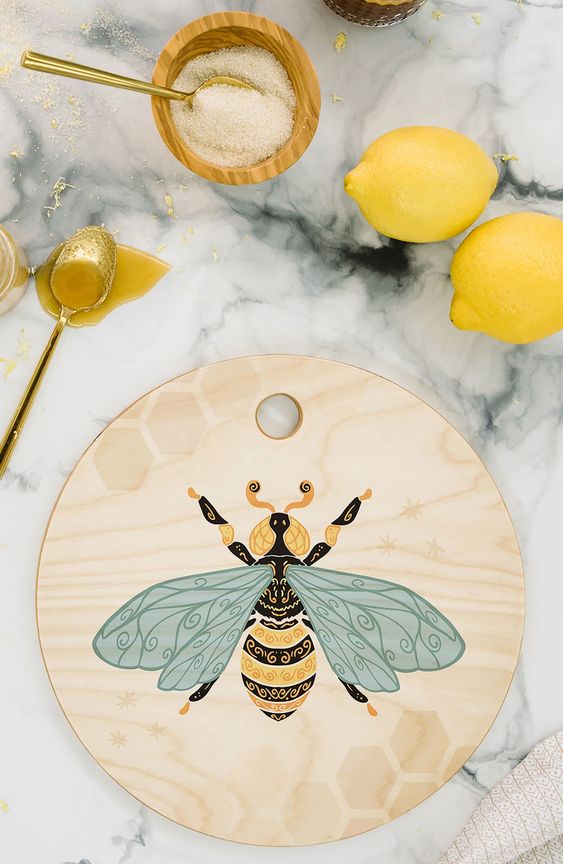 Marble counter with 2 lemons and a round cutting board with a bee motif