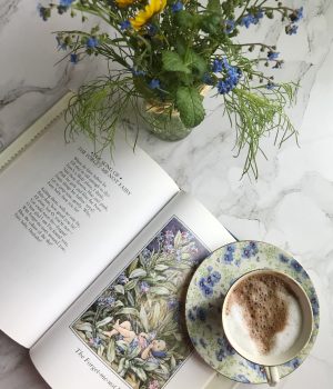 friday favorites cup oc hot chocolate on a flowered saucer jar of wildflowers and a flower fairies book