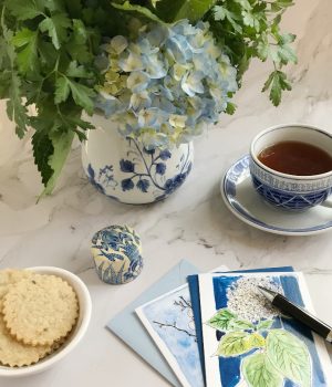 lavender lemon shortbread cookies in a bowl with a blue and white chinoiserie vase filled with flowers and a cup of tea