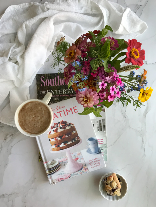 flatlay Cath Kinston tea time book a jar of flowers and a cup of chocolate