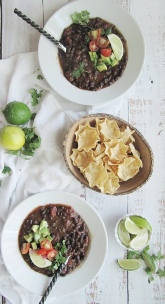 easy black bean soup 2 white bowls wood bowl of scoops chips and limes-2