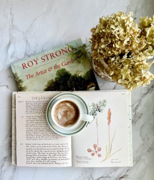flatlay with 2 books dried hydragneas and a cup of hot chocolate