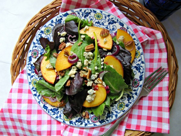 Peach salad on a colorful plate sitting on a pink and white gingham napkin. 
