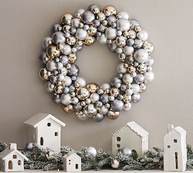 Christmas wreath made of silver and gold balls hanging above white christmas houses