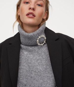 Girl wearing a great turtleneck sweater and a black blazer with a circle brooch