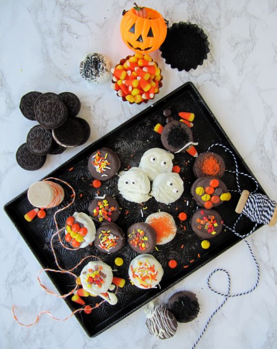baking tray filled with chocolate covered halloween Oreos and candy