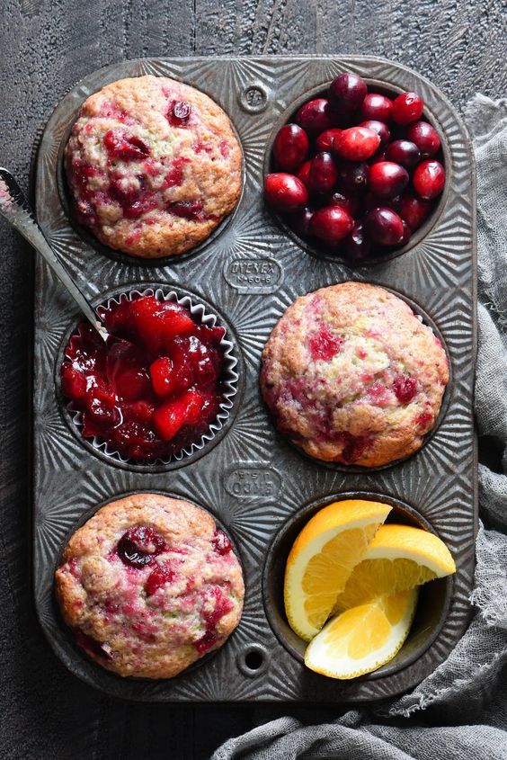 cranberry sauce muffins in a tin with oranges and fresh cranberries. 