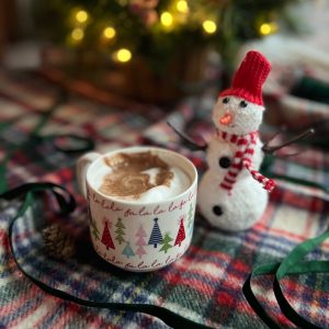 hot chocolate in a cup with fa la la la la and a snowman