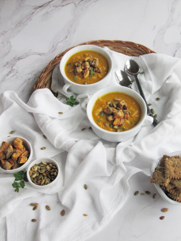 Turmeric sweet potato and pumpkin soup with white bowls on a white cloth.