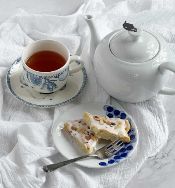 Almond Puff Pastry Swedish Kringler on a blue and white plate with a cup of tea and w white teapot. 