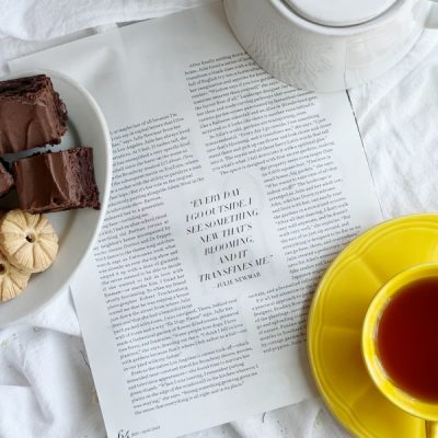 Flatlay with magazine article, plate of cookies and brownies and a cup of tea.