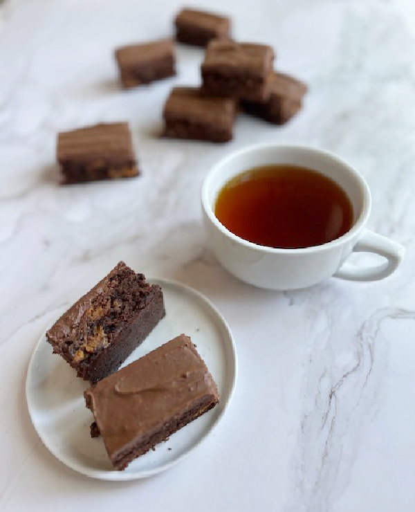 dulce de leche brownies on a stack and two on a plate with a cup of tea. 