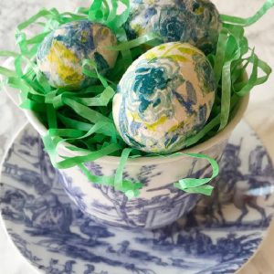 green and blue eggs in a blue and white tea cup.