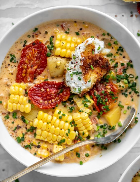 A large white bowl of sun dried tomato corn chowder. 