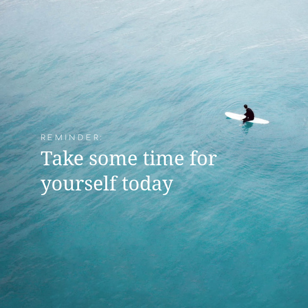 A man kneeling on a surf board in the ocean with text overlay Reminder Takes some time for yourself today. 