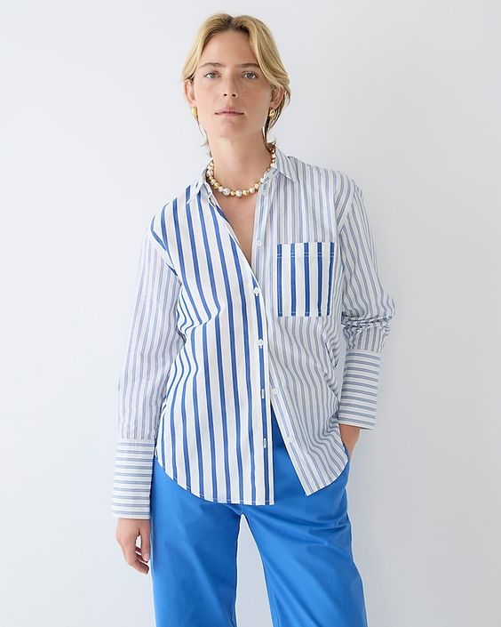 Woman wearing blue pants and w blue and white stripe button down shirt. 